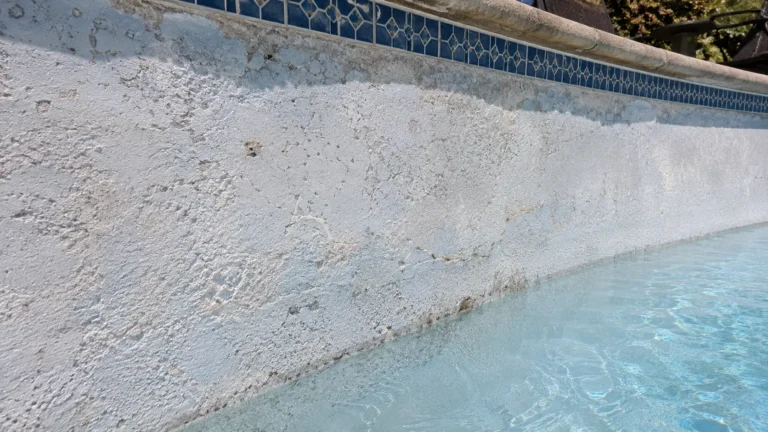 Damaged pool plaster showing surface breakdown along the waterline